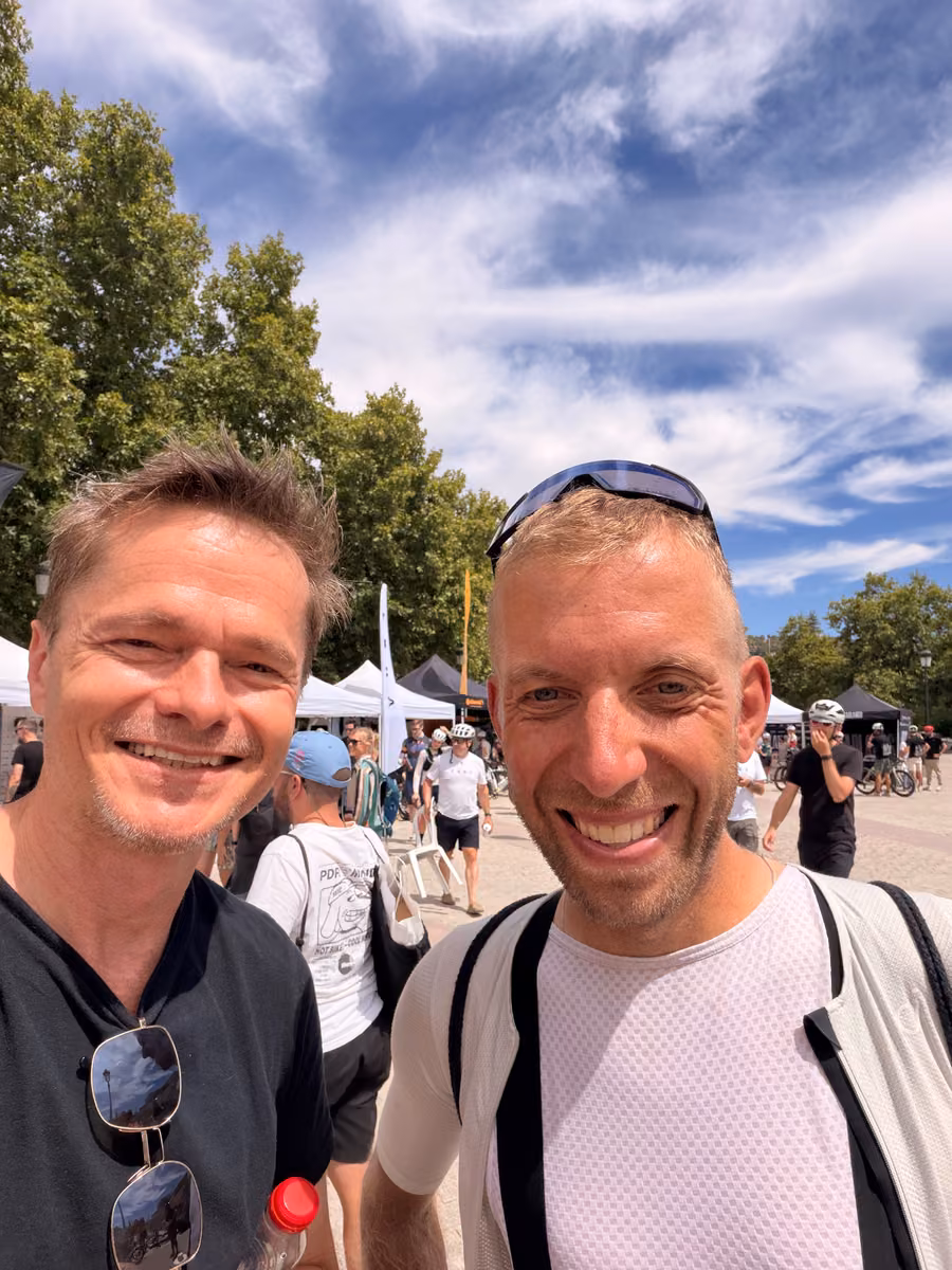 Two people smiling for a selfie beside the event tents.