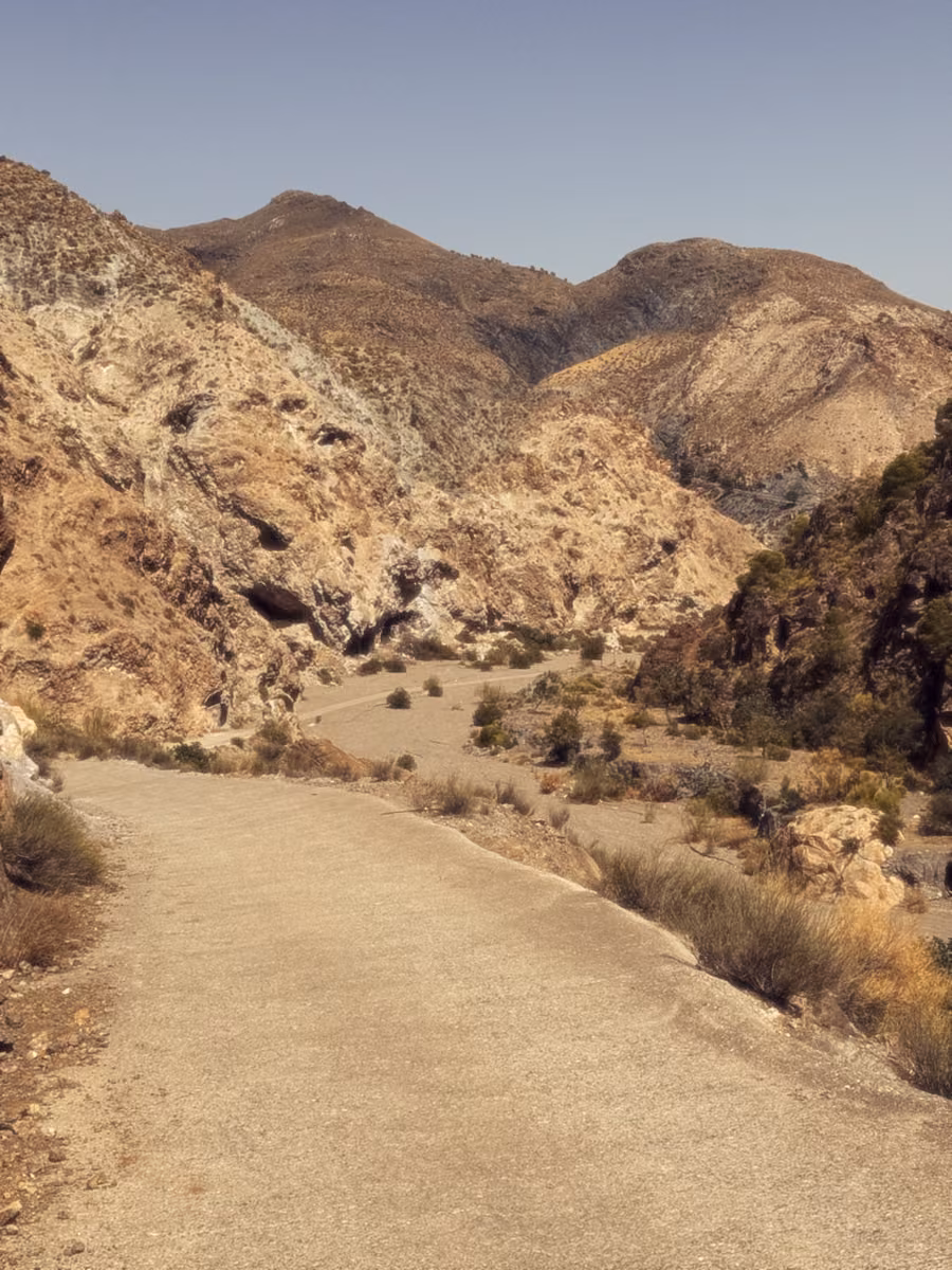 A pale road curves into a dry, rocky valley.