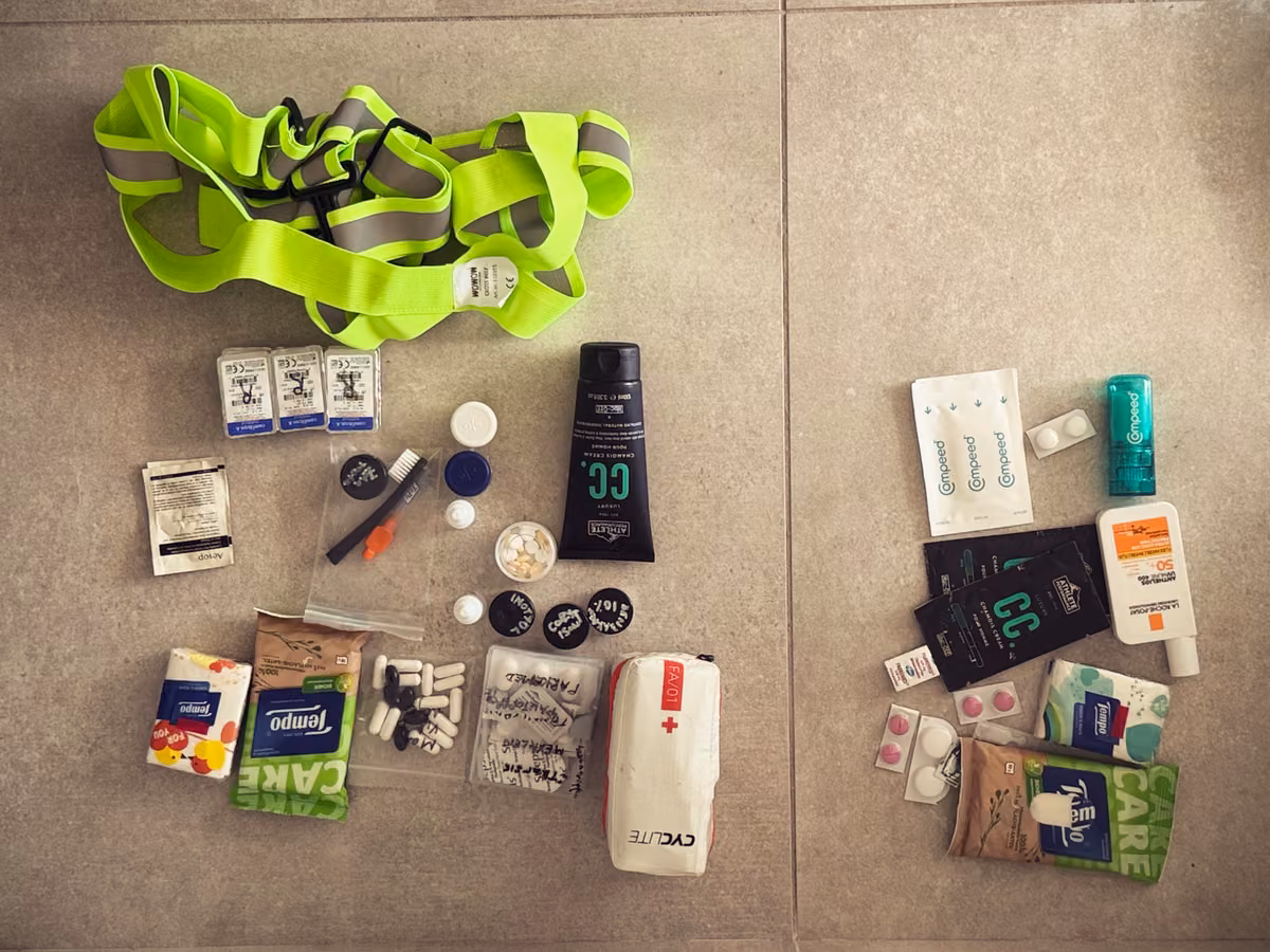 Reflective straps, toiletries, sunscreen and first-aid supplies arranged on tiles.
