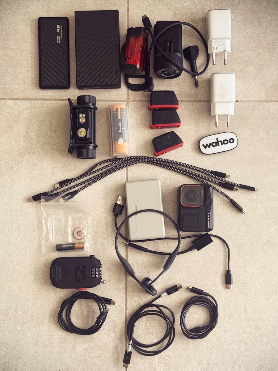 Power banks, lights, batteries, chargers and cables laid out before packing.