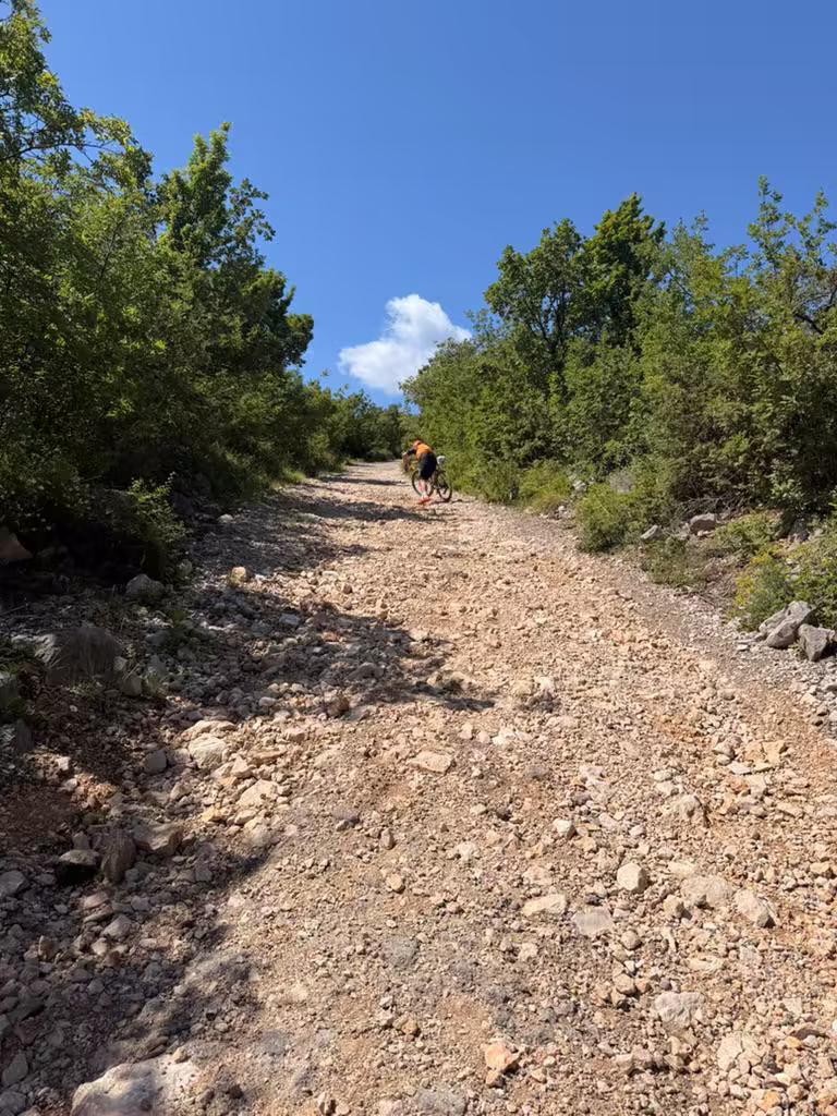 Rider pushing up steep rocky gravel in Croatia
